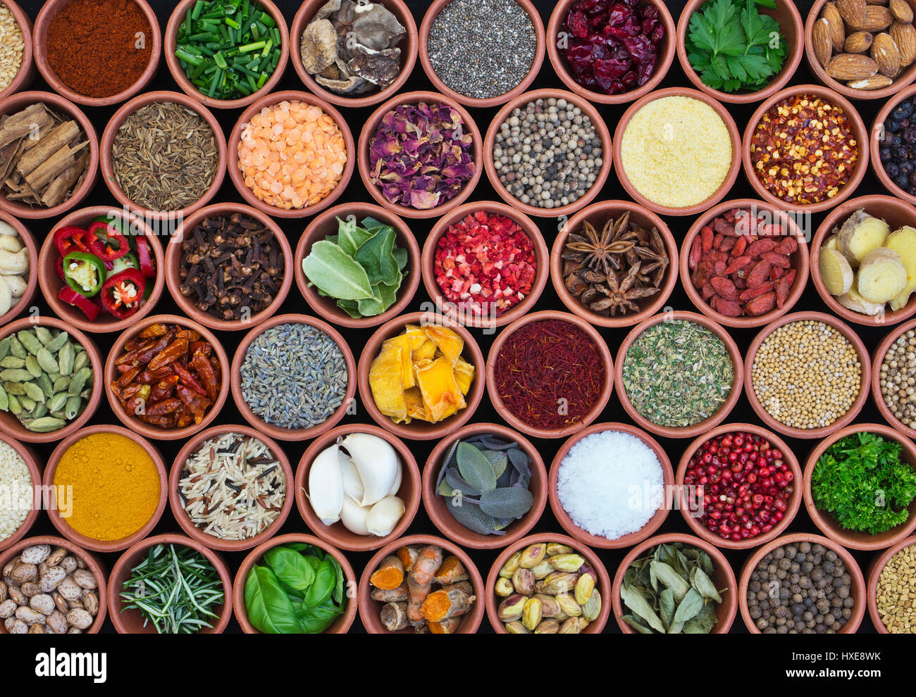 Cooking ingredients. Herbs, spices, nuts, seeds and pulses in round  terracotta pots pattern Stock Photo
