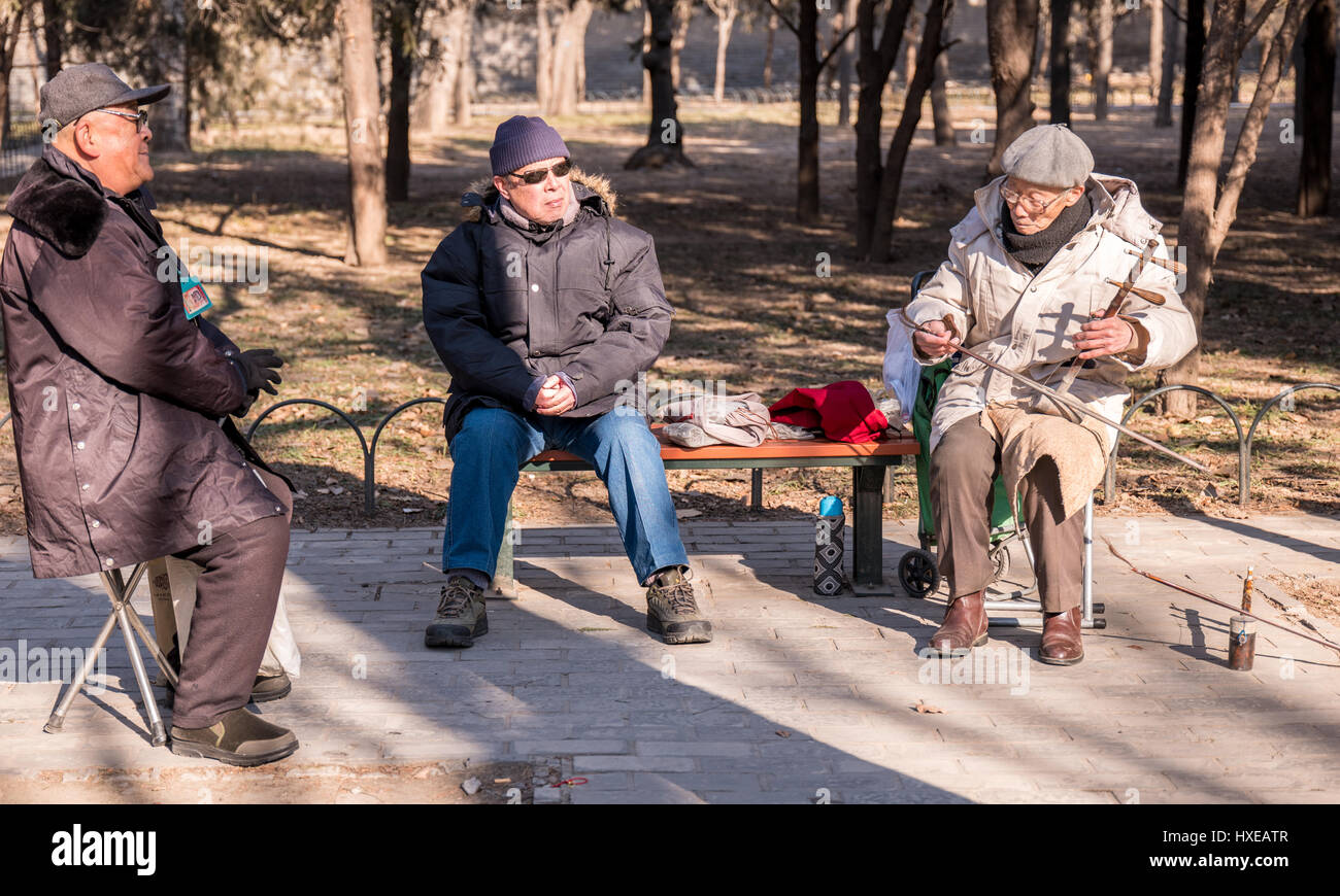 Elderly Chinese man playing the two stringed Chinese violin or Erhu on a winter day at the Temple of Heaven Park in Beijing. Stock Photo