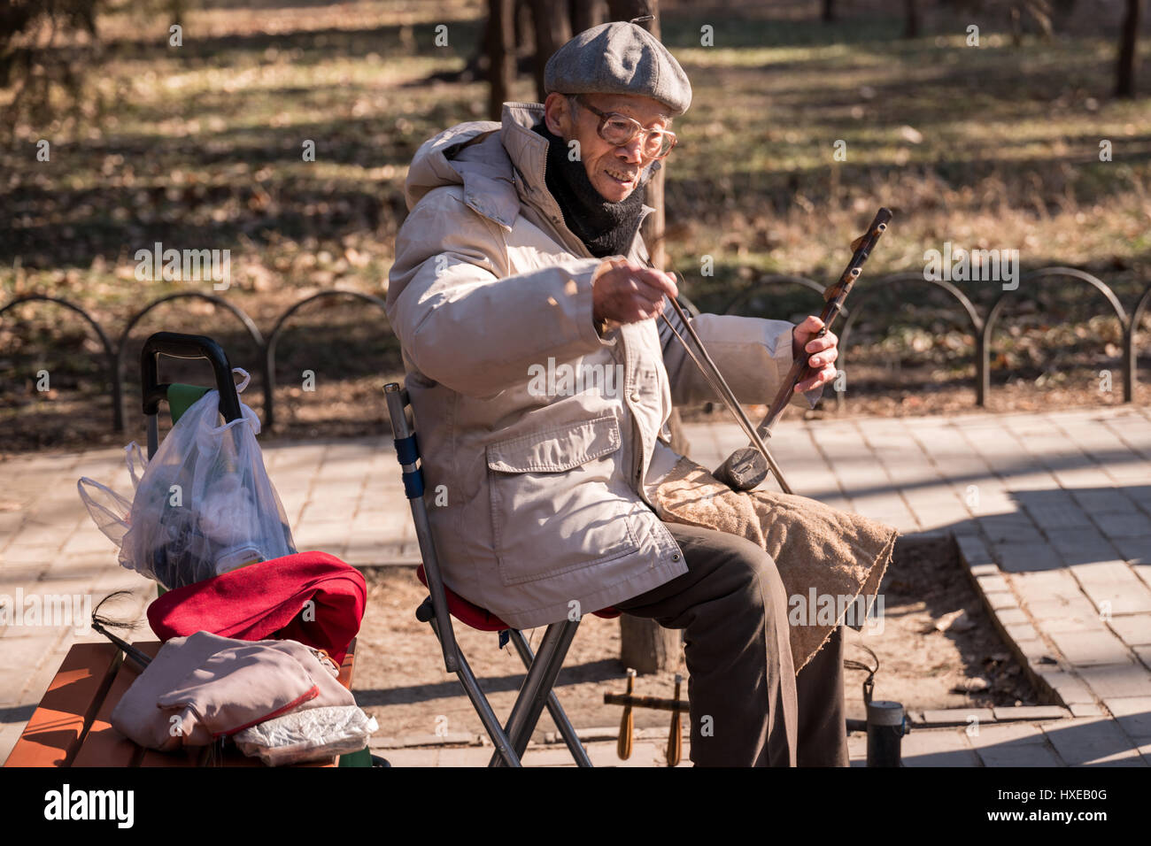 Elderly Chinese man playing the two stringed Chinese violin or Erhu on ...