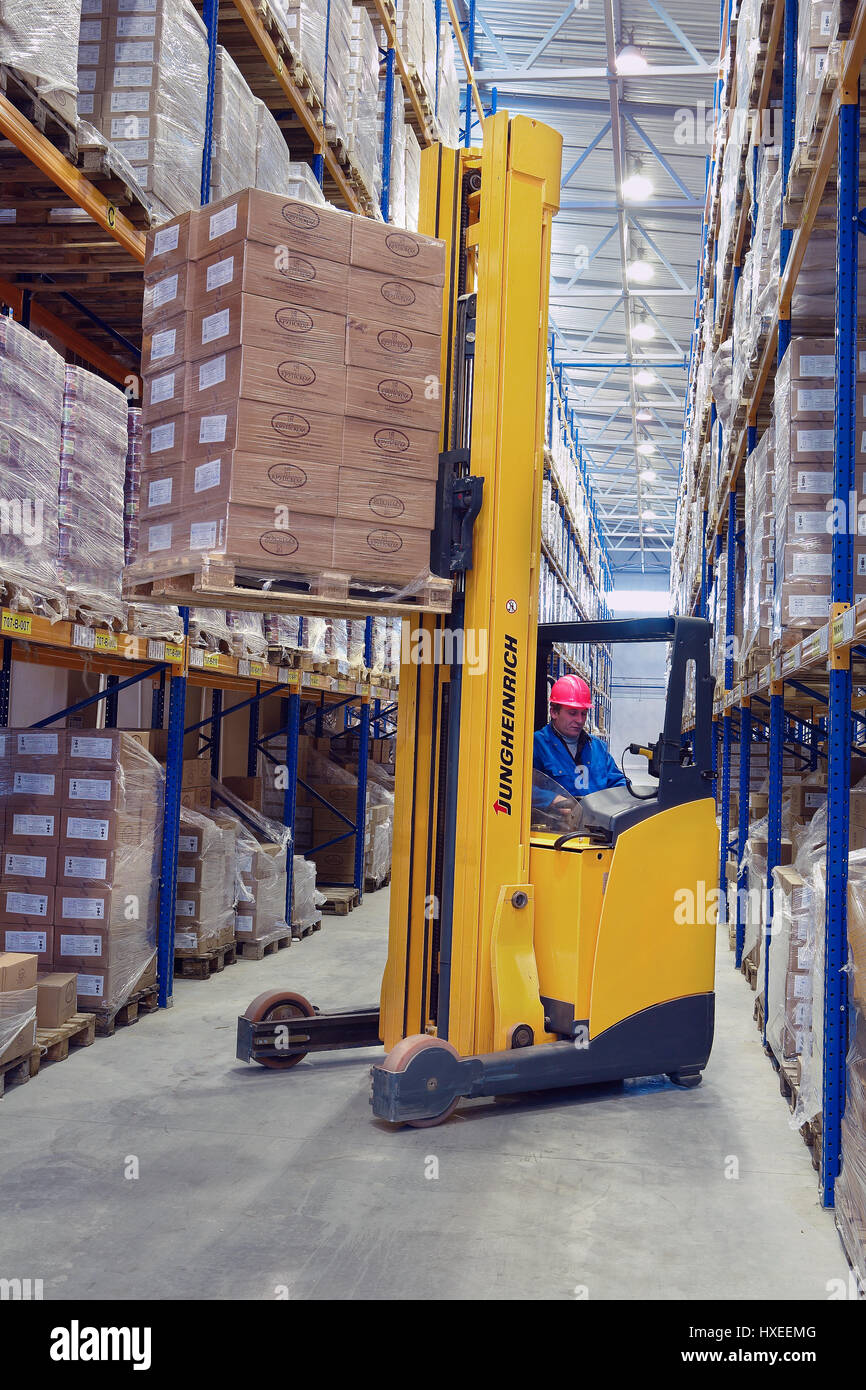 St. Petersburg, Russia - November 21, 2008: Yellow Forklift pallet truck lifts the pallet in the narrow aisle warehouse. Forklift raises palletising o Stock Photo