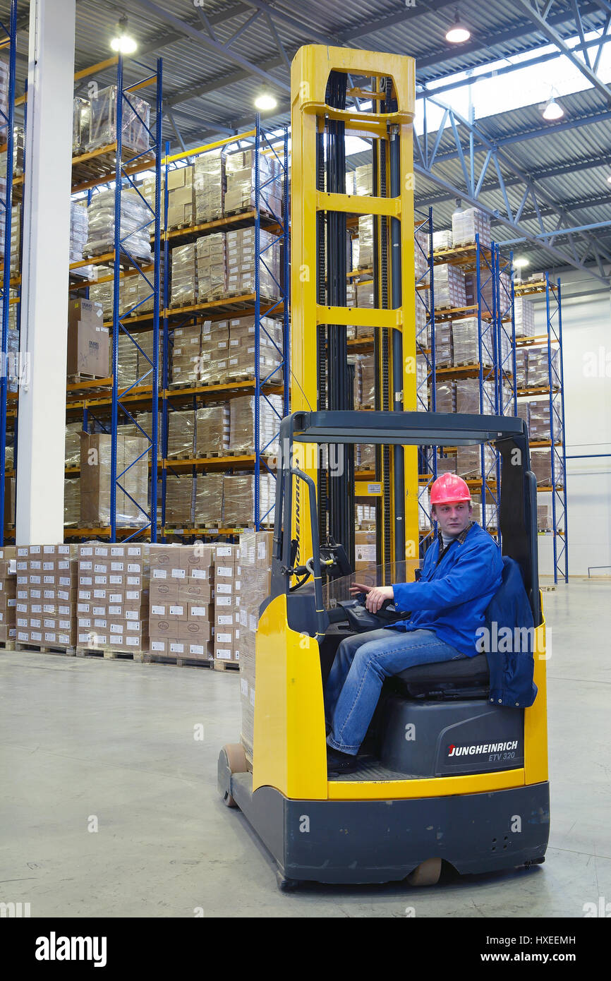 St. Petersburg, Russia - November 21, 2008: The driver of a yellow forklift truck operates, in warehouses, sitting in the workplace. Stock Photo