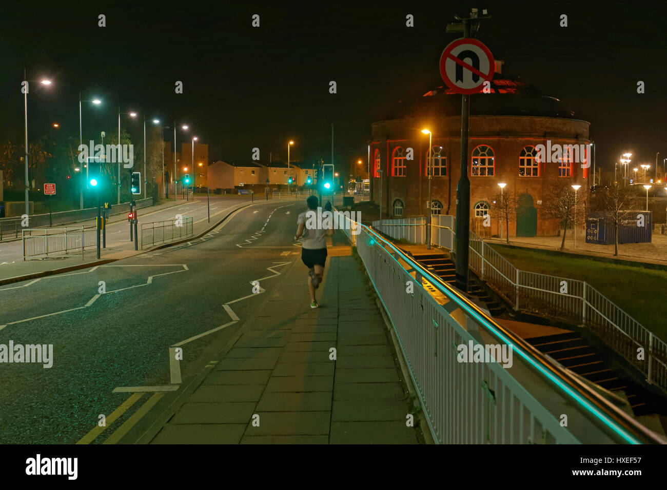 runner on Glasgow street  night crossing bridge no u turn green lights on traffic lights go Stock Photo