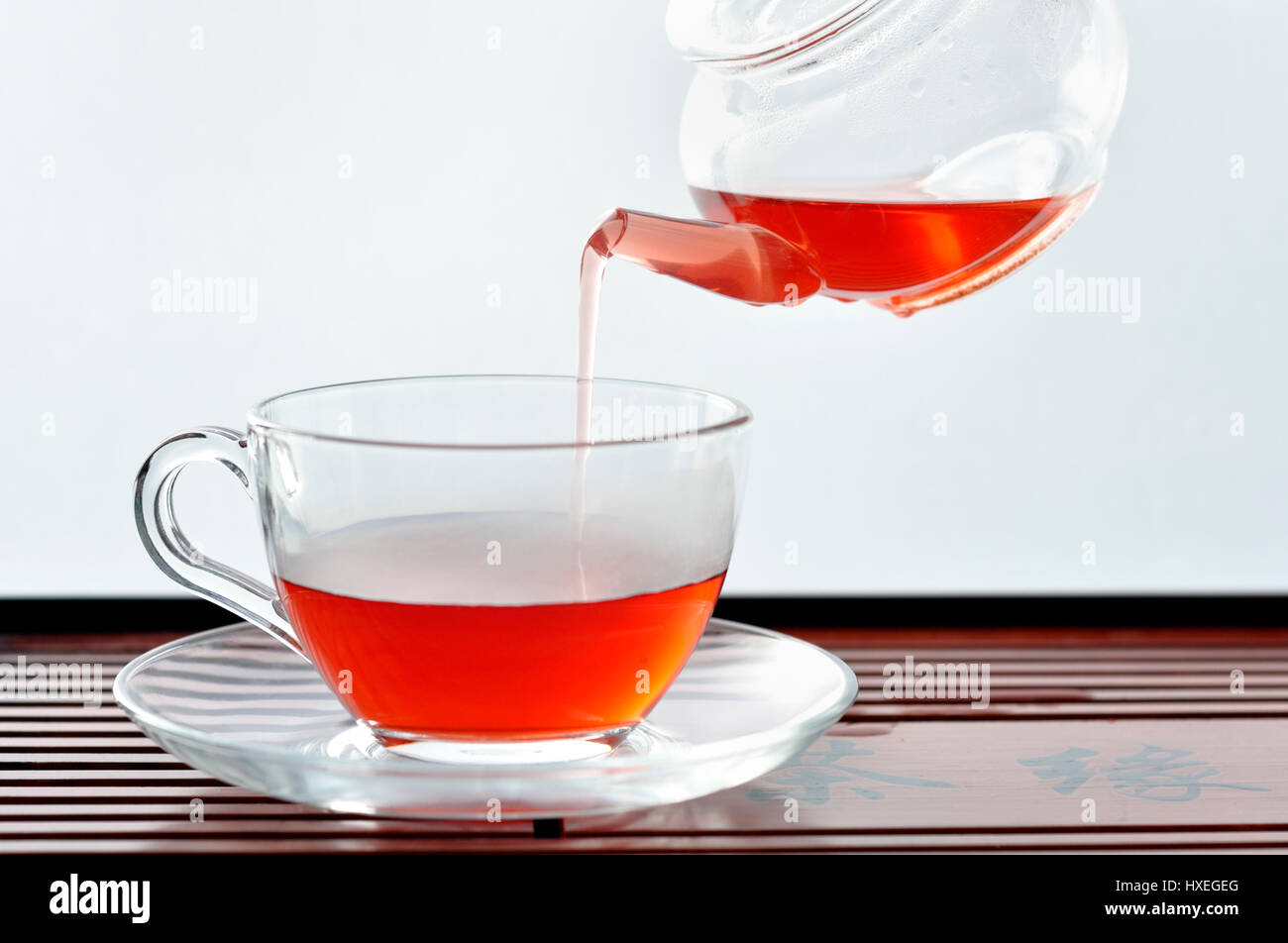 Pouring tea into a clear glass cafe style cup from teapot Stock Photo