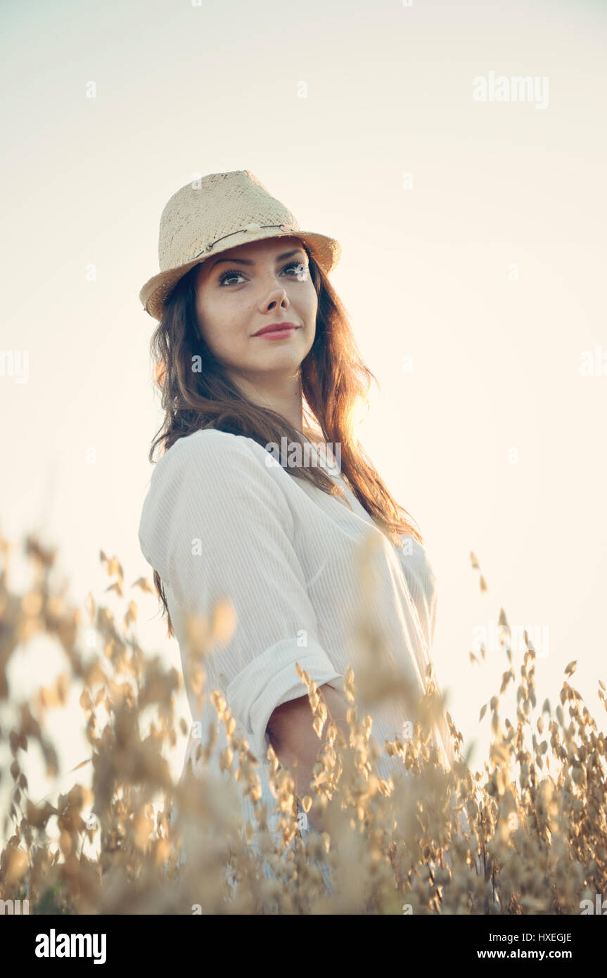 Young woman standing in oat field Stock Photo