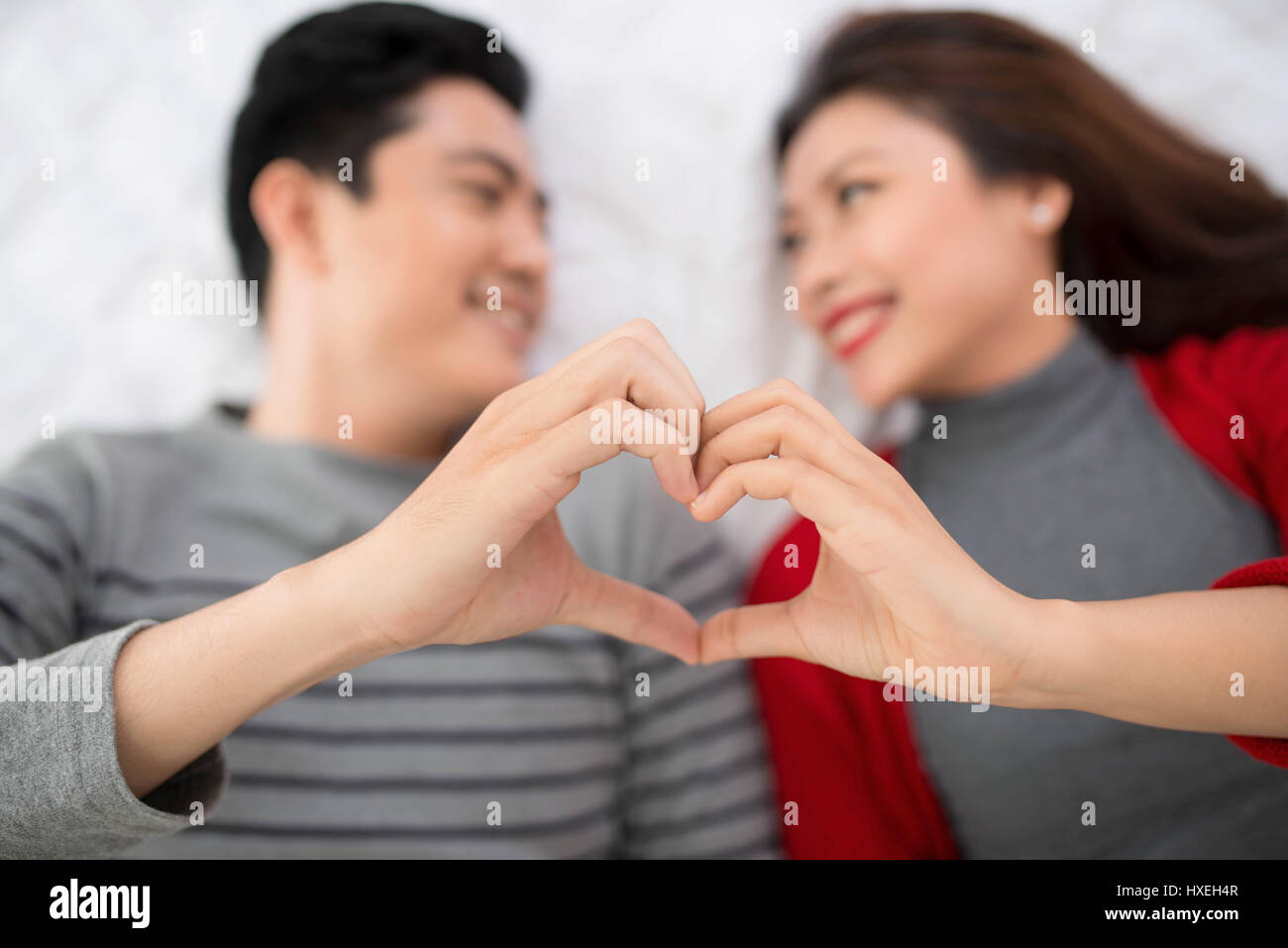 Jovial loving gay couple sitting on bed while looking at Jovial loving gay couple sitting on bed while looking at