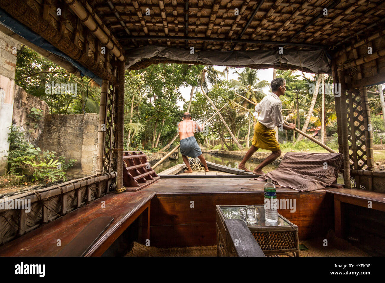 Two men punting environmentally friendly house boat in Kerala backwaters, southern India Stock Photo