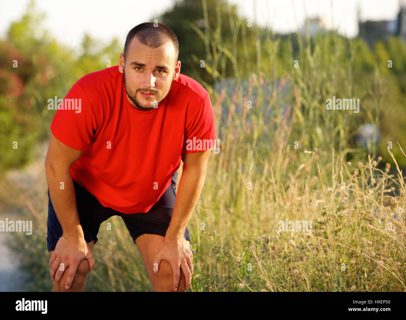 Tired young man bending down relaxing after workout Stock Photo - Alamy