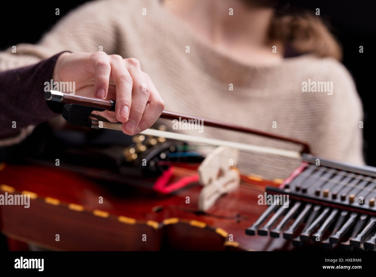 woman playing an ancient medieval musical instrument, modern reconstruction of an antique nyckelharpa, often used in folk or baroque musical concerts  Stock Photo