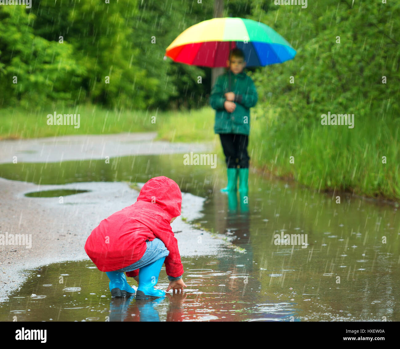 Children walking in wellies in puddle on rainy weather Stock Photo