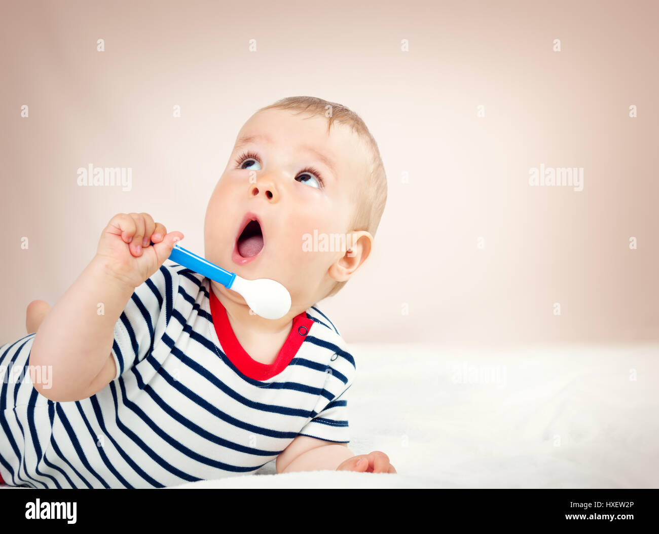 Nine month old baby lying in the bed with spoon Stock Photo Alamy