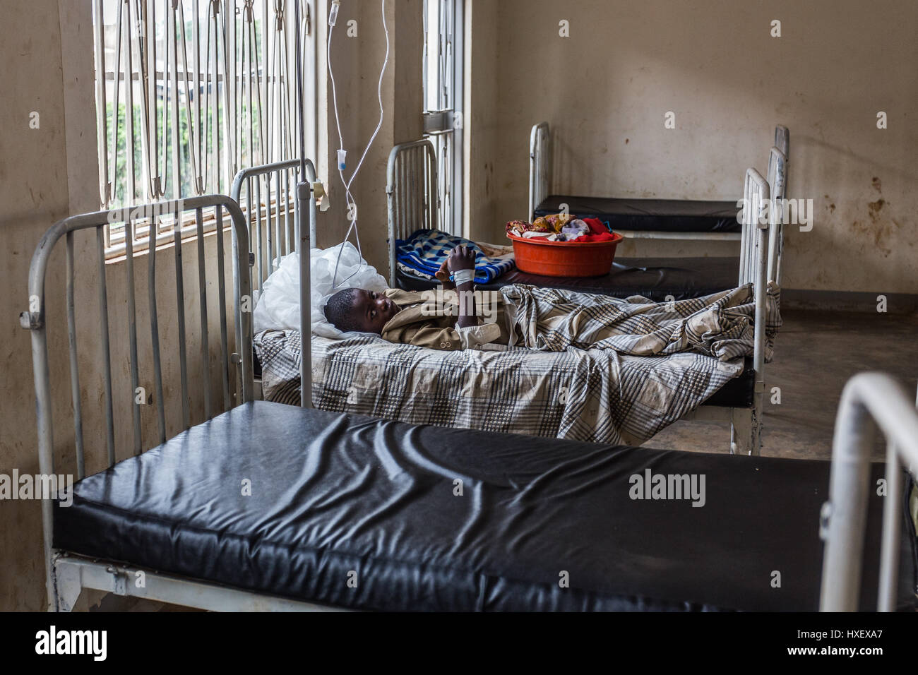 Young child patient lying alone in his hospital bed in a rural clinic in Eastern Uganda Stock Photo