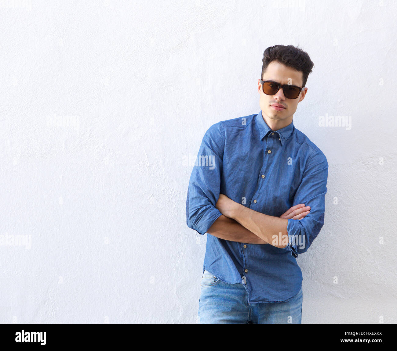 Portrait of a confident young man posing with sunglasses standing ...