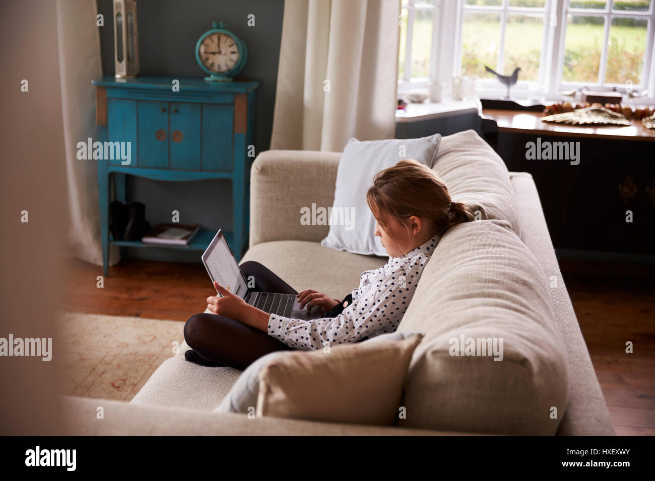 Girl Sitting On Sofa At Home Using Laptop Computer Stock Photo