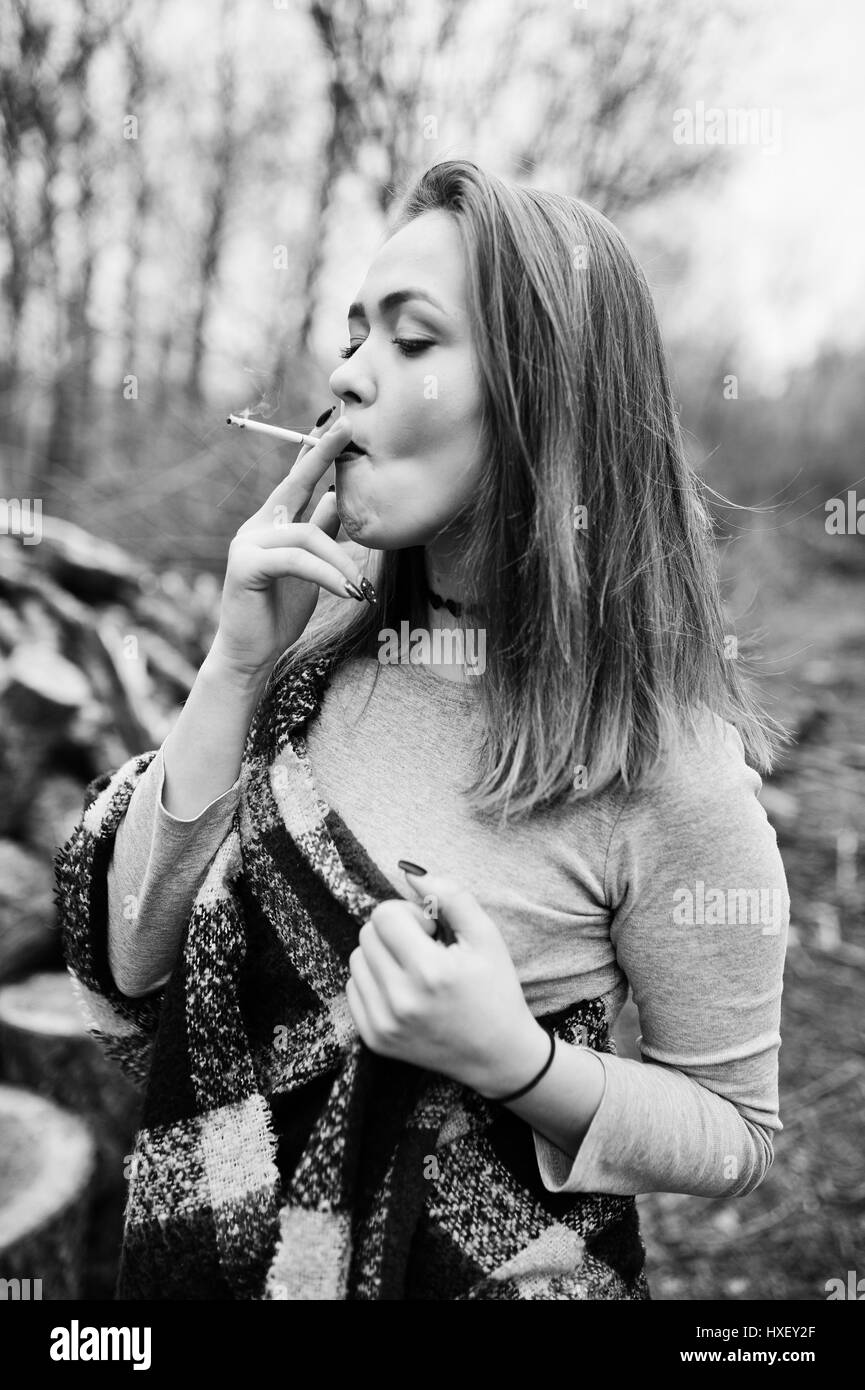 Young girl smoking cigarette outdoors background wooden stumps ...