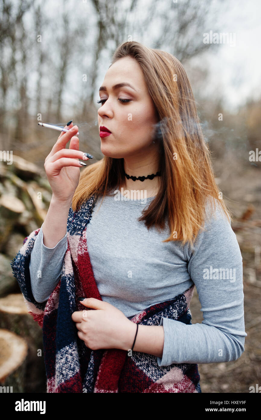 Young girl smoking cigarette outdoors background wooden stumps Stock