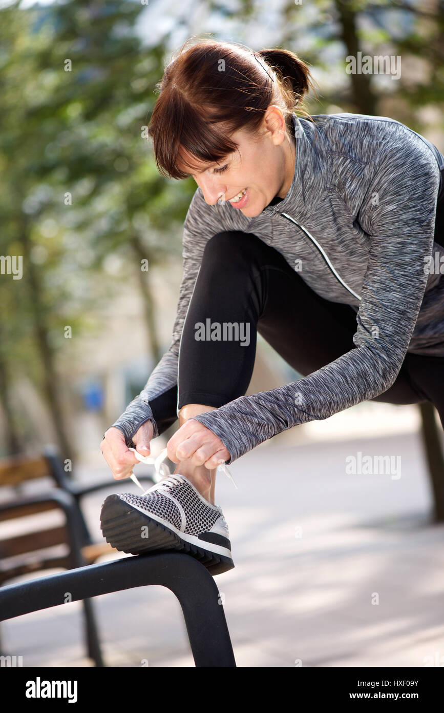 Portrait of a woman tying shoelace before workout Stock Photo - Alamy - Shoelace Tying For Adults Without Prior Technique