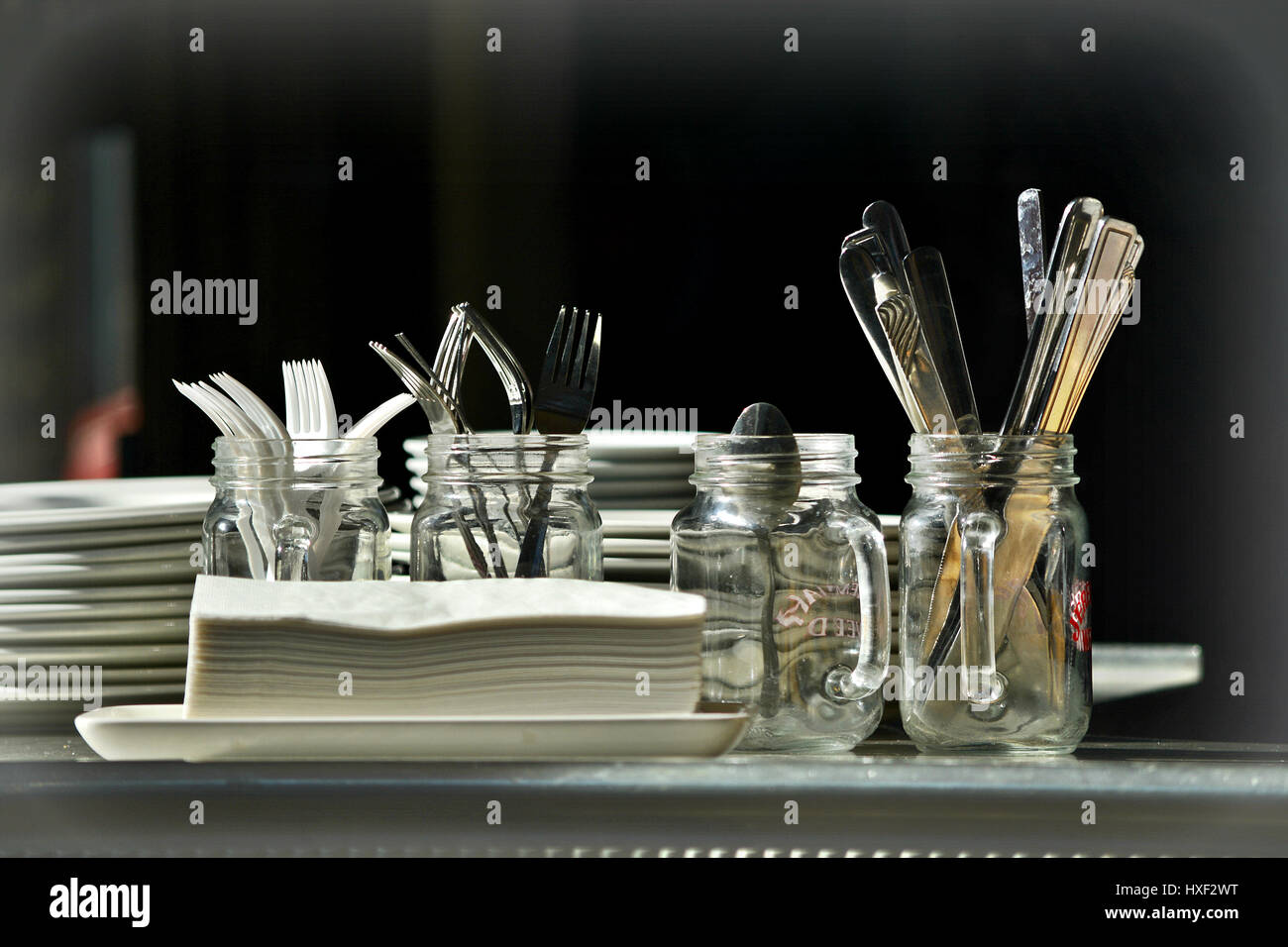 An Almost Black And White Still Life Of Plates, Jars And Cutlery Stock Photo