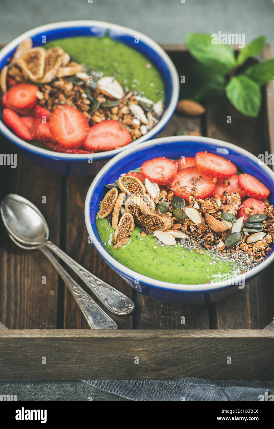 Healthy breakfast, green smoothie bowls with granola, fruit, seeds