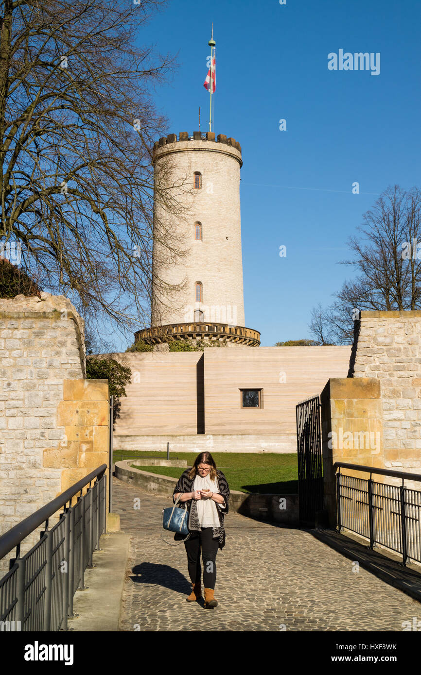 Woman walking away from Sparrenburg Castle, Bielefeld, Germany checks her phone, showing a lack of interest Stock Photo