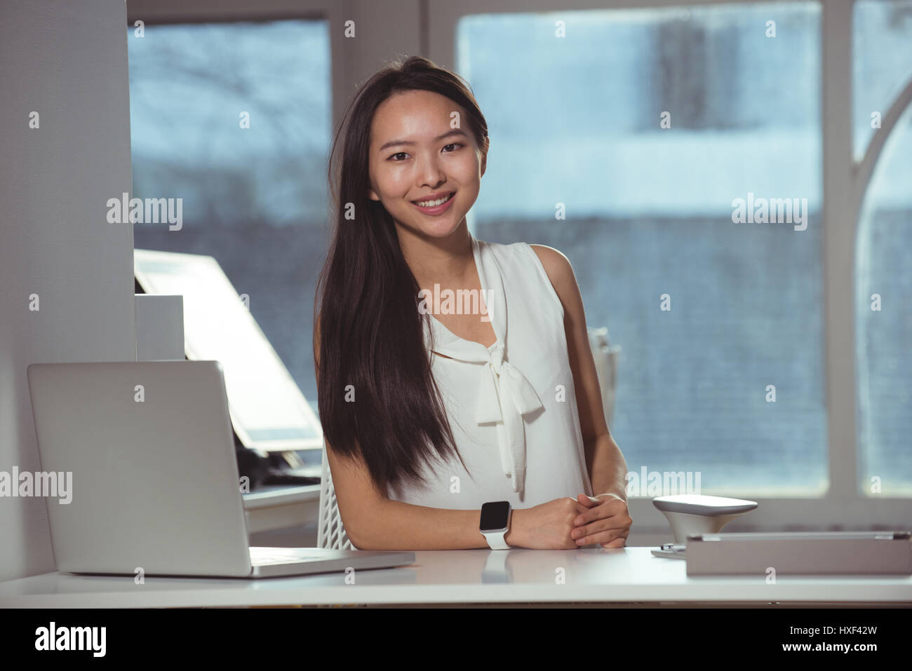 Portrait of female executive smiling while sitting at desk Stock Photo ...