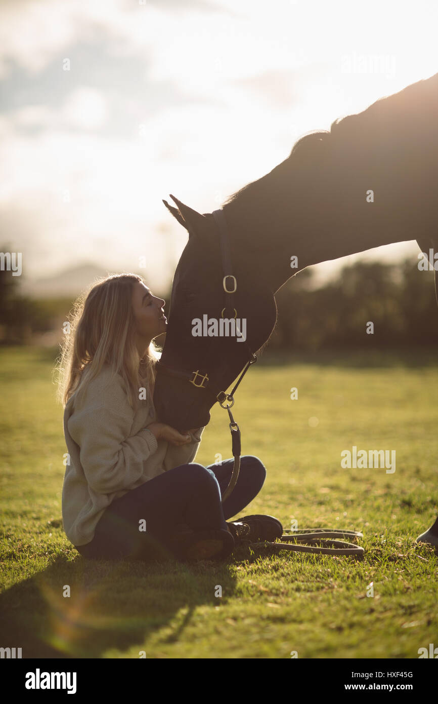Woman petting horse in farm on a sunny day Stock Photo