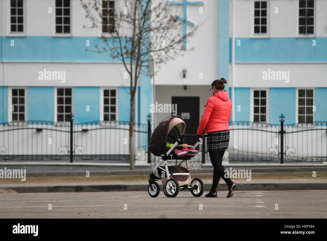 young mother promenade with her little baby into pram in spring day ...