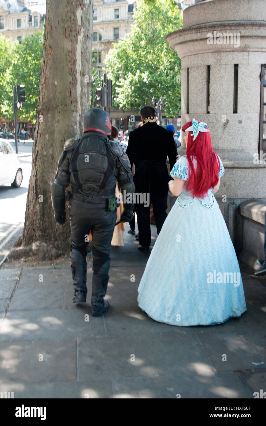 Man in Judge Dredd costume and woman in Disney Princess costume walking  away along a street in central London Stock Photo - Alamy