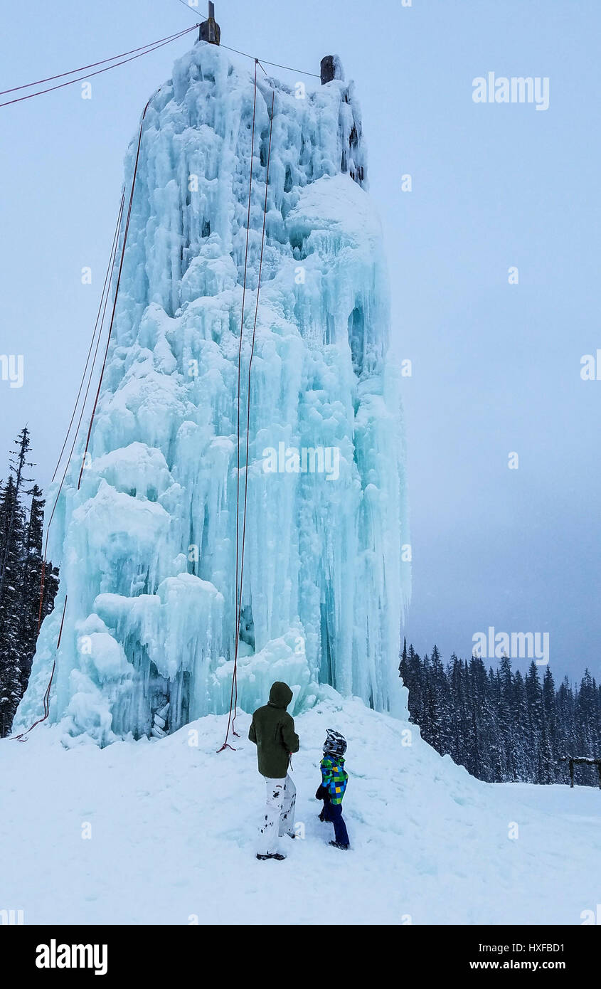 Father and son check out the 60 foot tall ice climbing tower in Happy Valley Adventure Park at Big White Ski Resort. One of a half dozen non ski winte Stock Photo