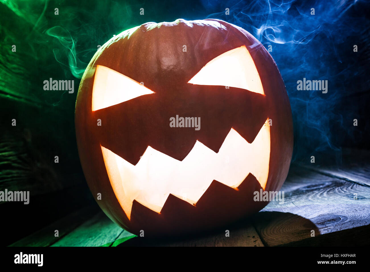 Closeup of glowing pumpkins for Halloween with blue and green smoke