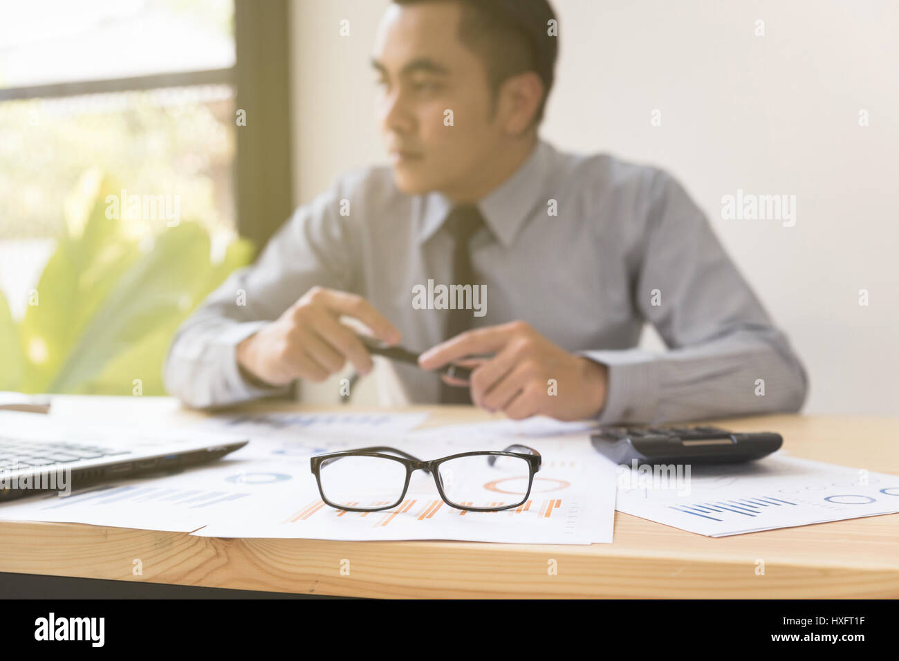 eyeglasses and calculator on desk wtih businessman analyzing report on