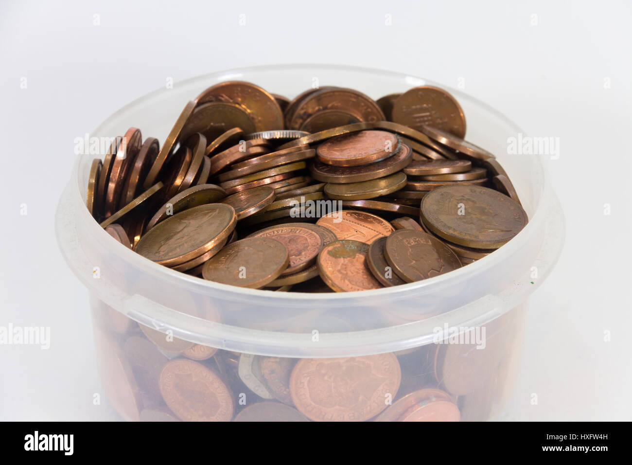 Quantity of UK coins, mostly copper one pence and two pence pieces, in a plastic tub. Stock Photo