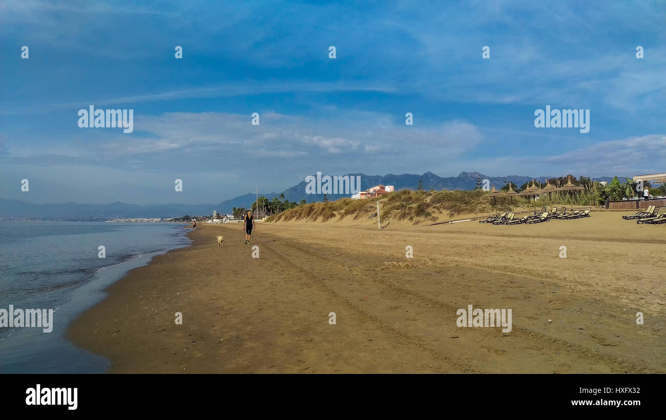 Quiet stretch of beautiful sandy beach in Costa Del Sol Spain near Marbella with woman running
