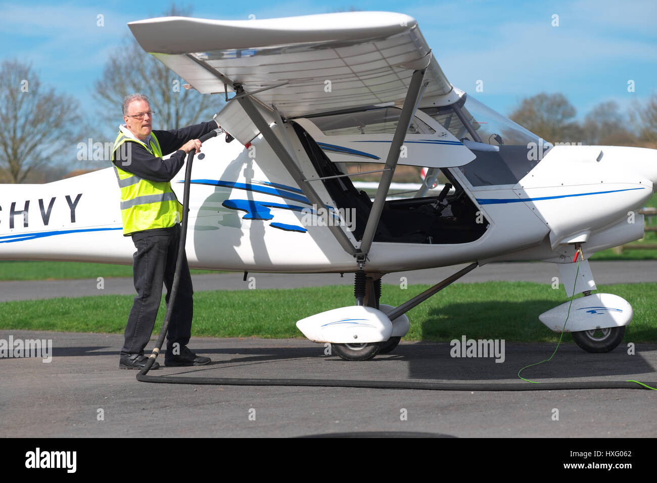 A pilot wearing a high viz jacket refuels his C42 microlight aircraft at Shobdon airfield UK Stock Photo
