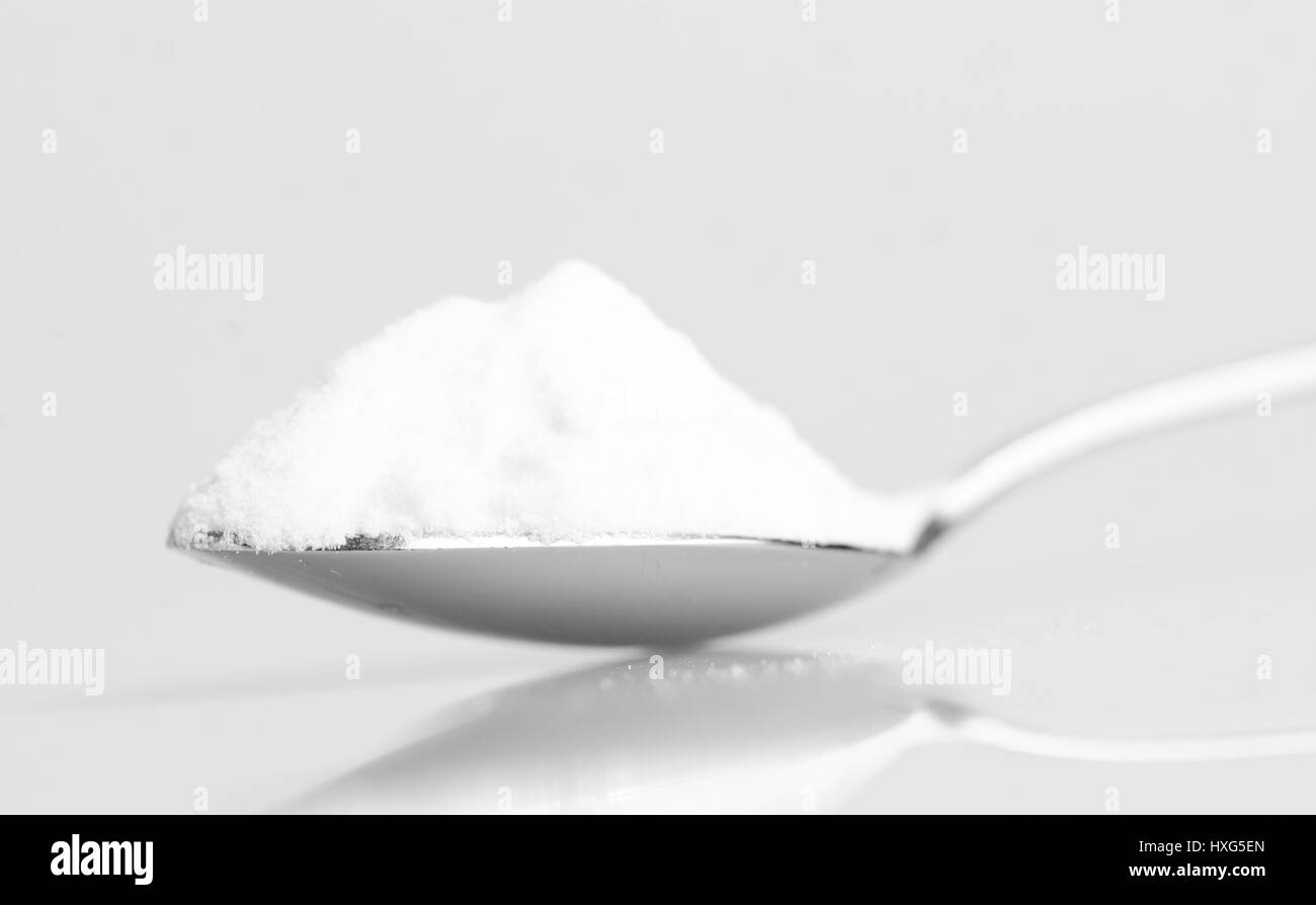 Baking soda in steel spoon isolated on grey background with reflexion Stock Photo