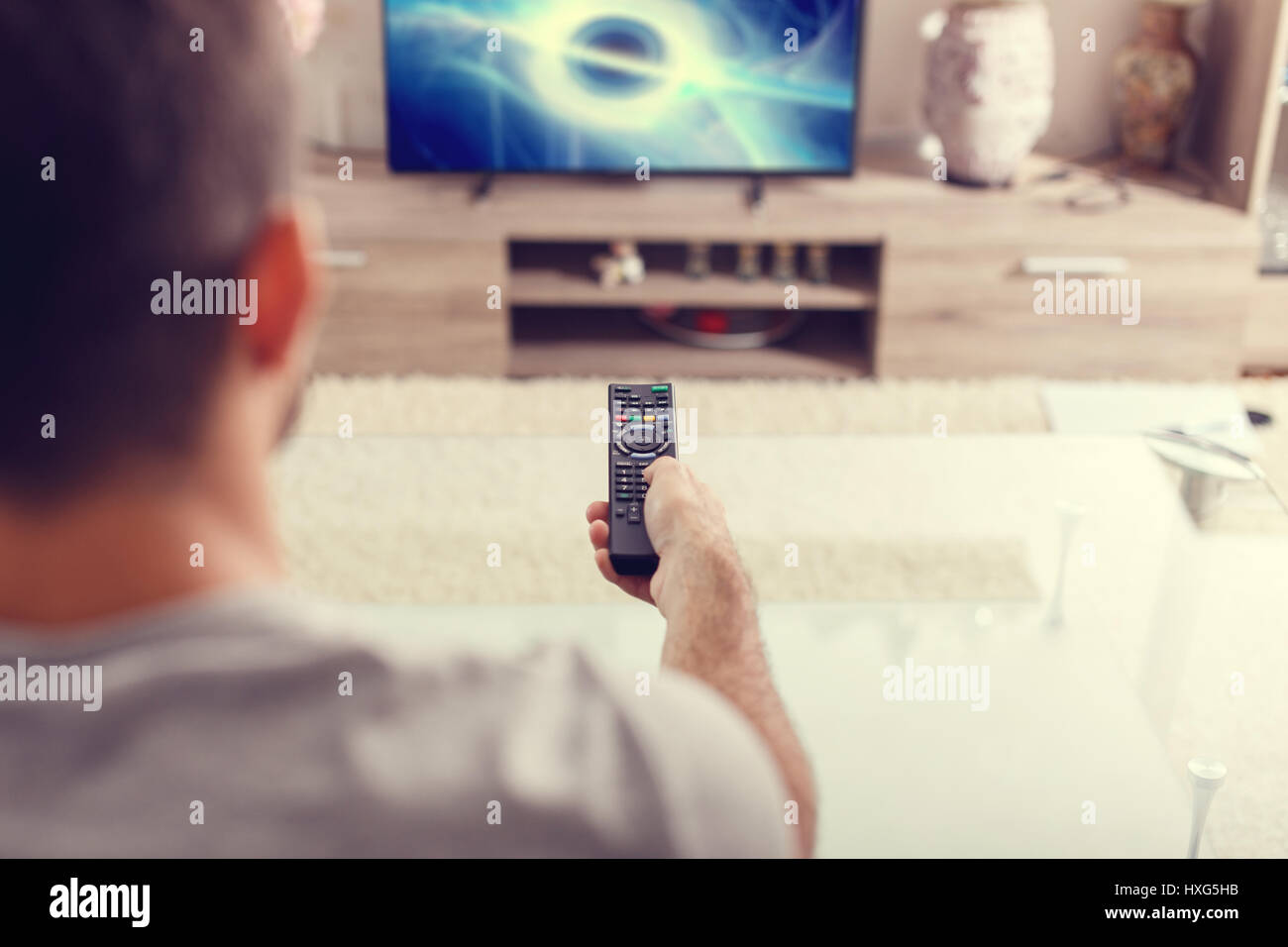 Man with remote control watching sci-fi at home in TV Stock Photo
