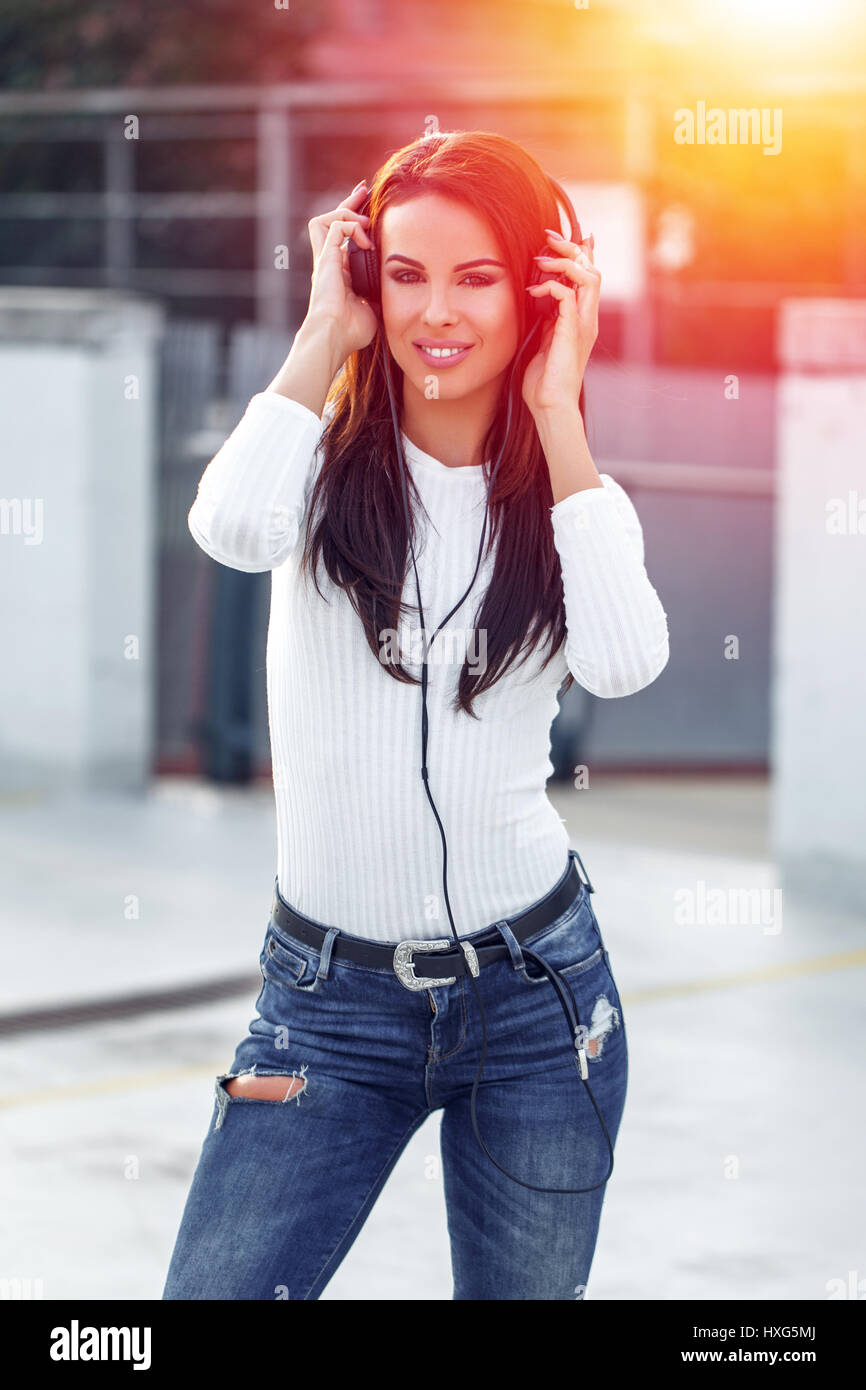 Young woman listening music by headphones in sunset at oudorr Stock Photo