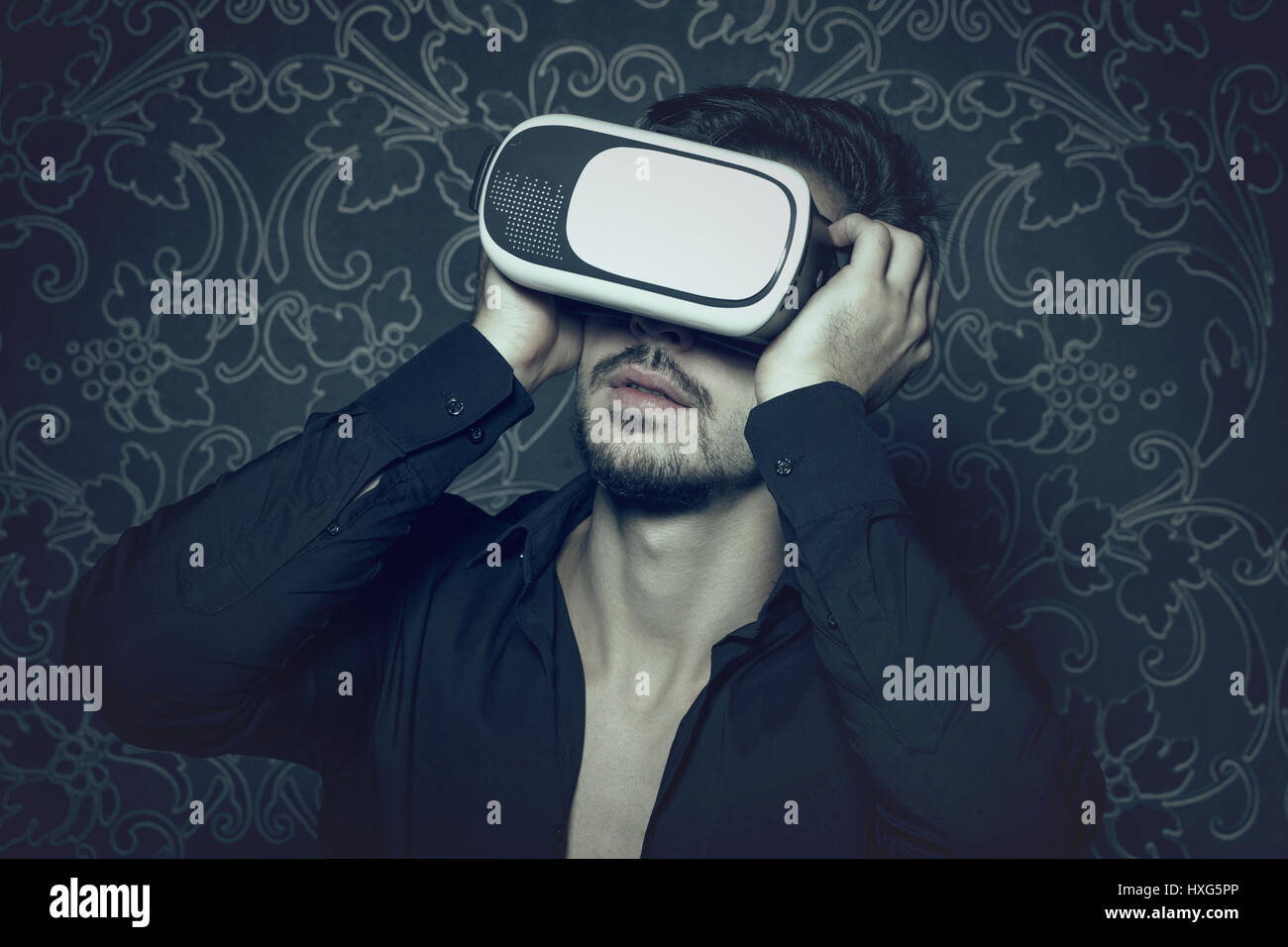 Young caucasian man in virtual reality headset enjoying simulation, in cinematic style Stock Photo