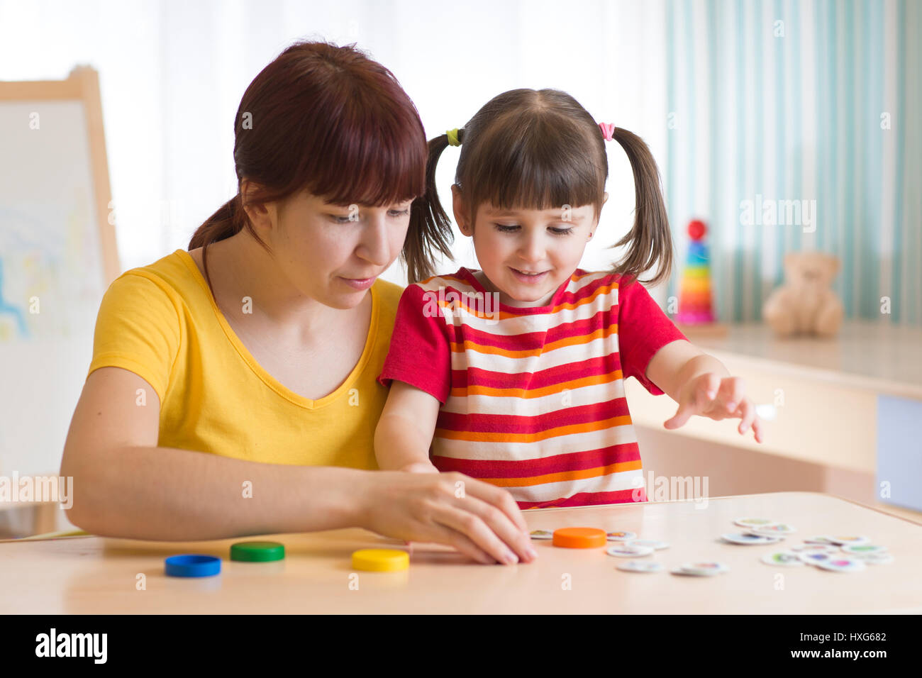 kid girl and mother playing together with puzzle toy Stock Photo