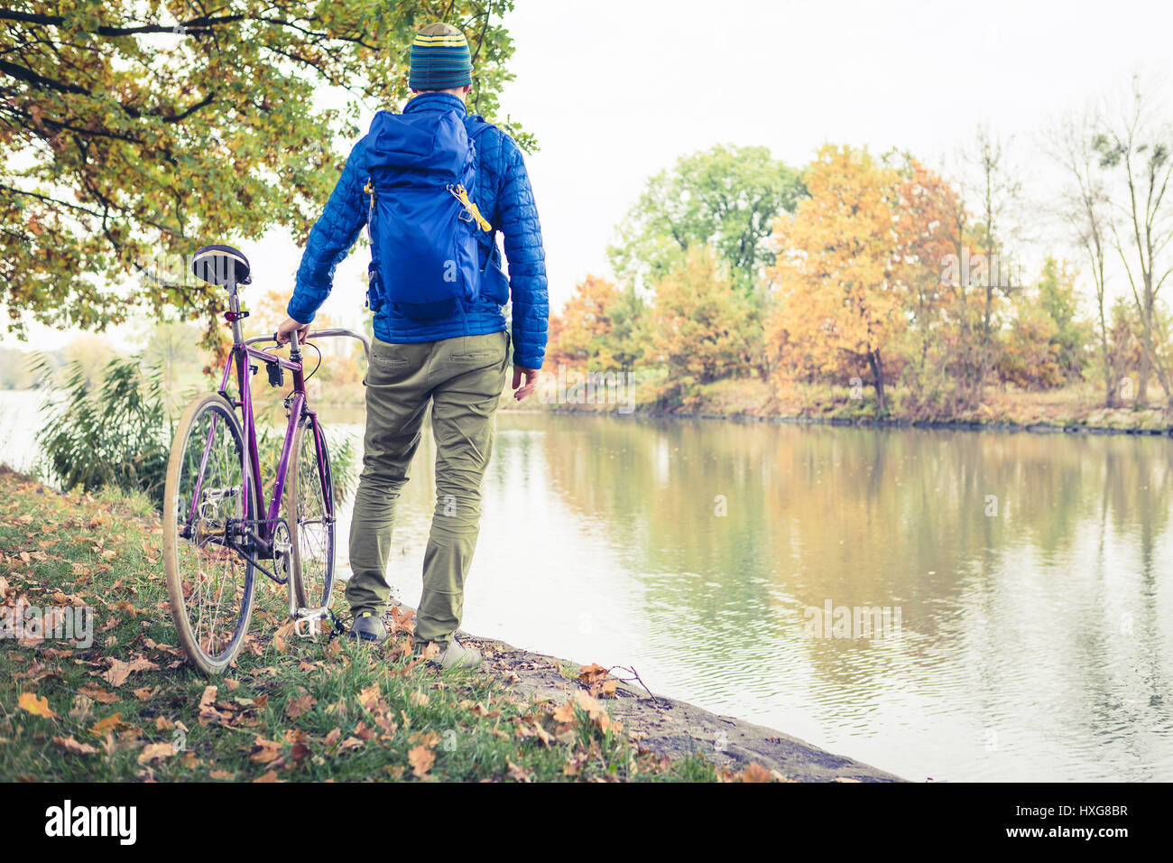 Man with road bike looking at river view in park. Male commuter and fixed gear bicycle relaxing in green park. Sport fitness motivation and inspiratio Stock Photo