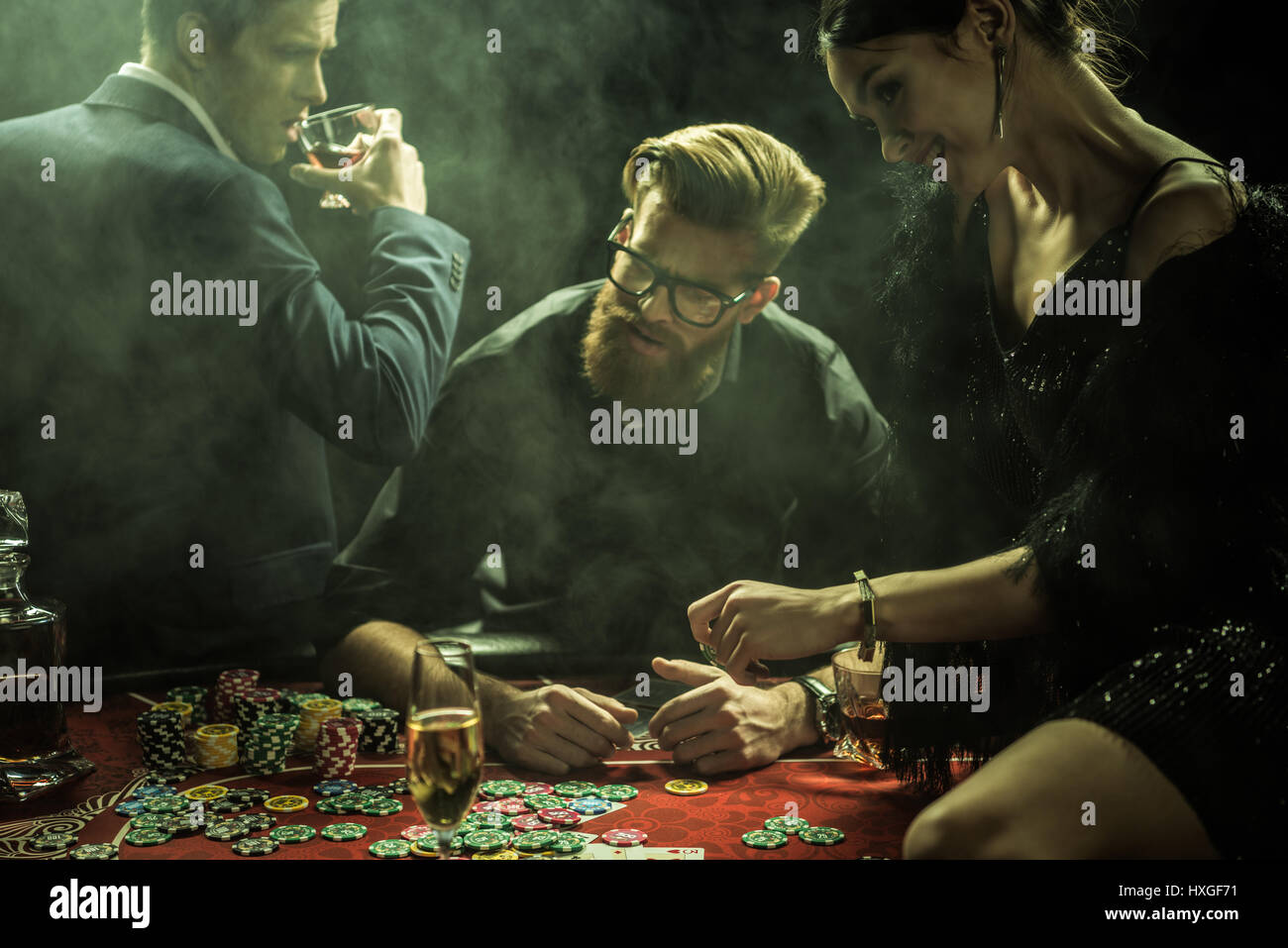 portrait of group of people with drinks playing poker in casino Stock Photo