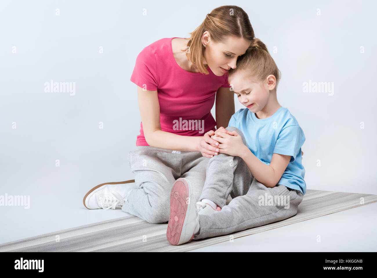 mother appeasing crying daughter during training on white Stock Photo