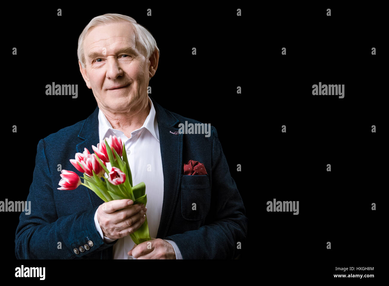 Senior man in suit holding tulips bouquet and smiling at camera, spring holiday concept Stock Photo