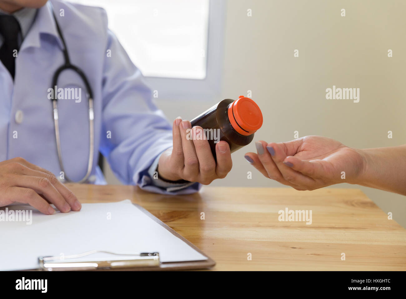 Doctor giving a consultation in his office, he is giving a prescription medicine to his female patient Stock Photo