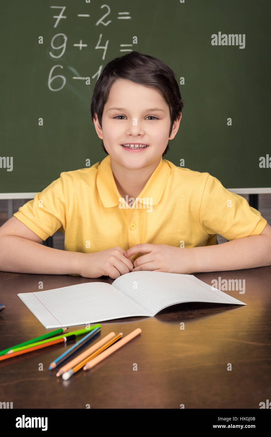 portrait of smiling boy sitting at table in classroom Stock Photo Alamy