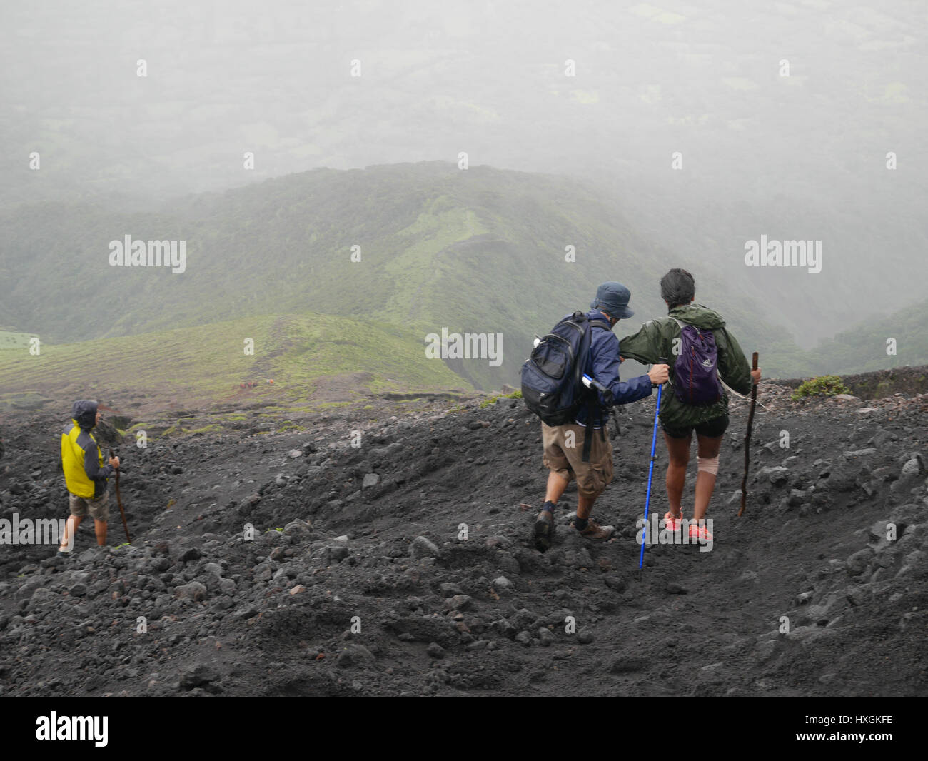 People hiking down from volcano, mountain in a group, Guide is helping ...