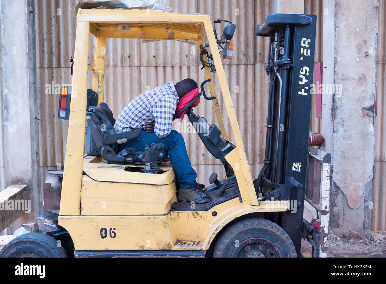 A man sleeps in the seat of his forklift at a textile factory in