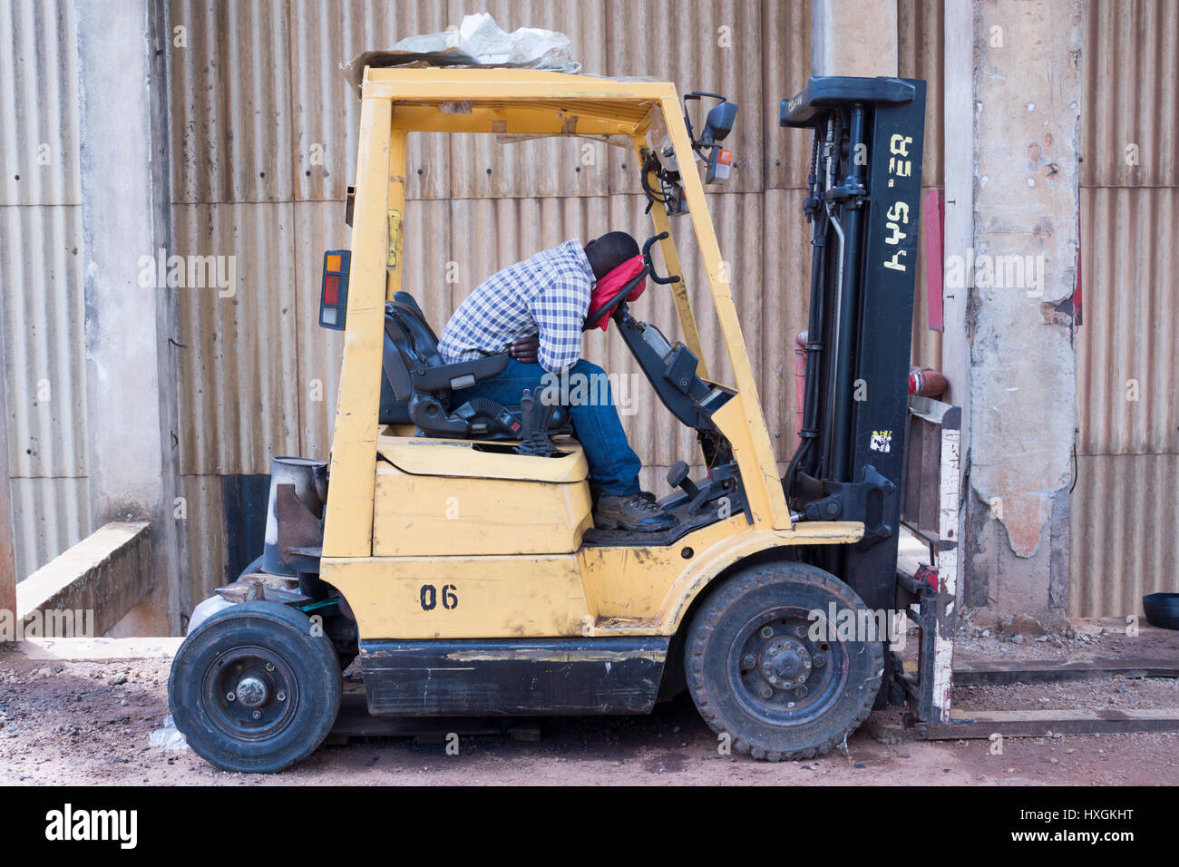 A man sleeps in the seat of his forklift at a textile factory in