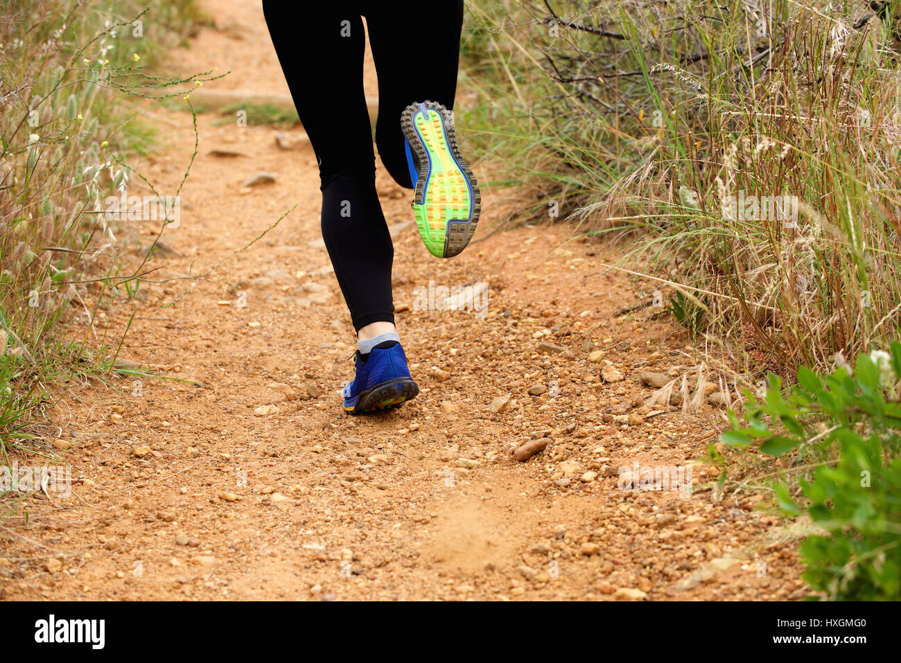 Close up of a woman's feet running on dirt road wearing sneakers and
