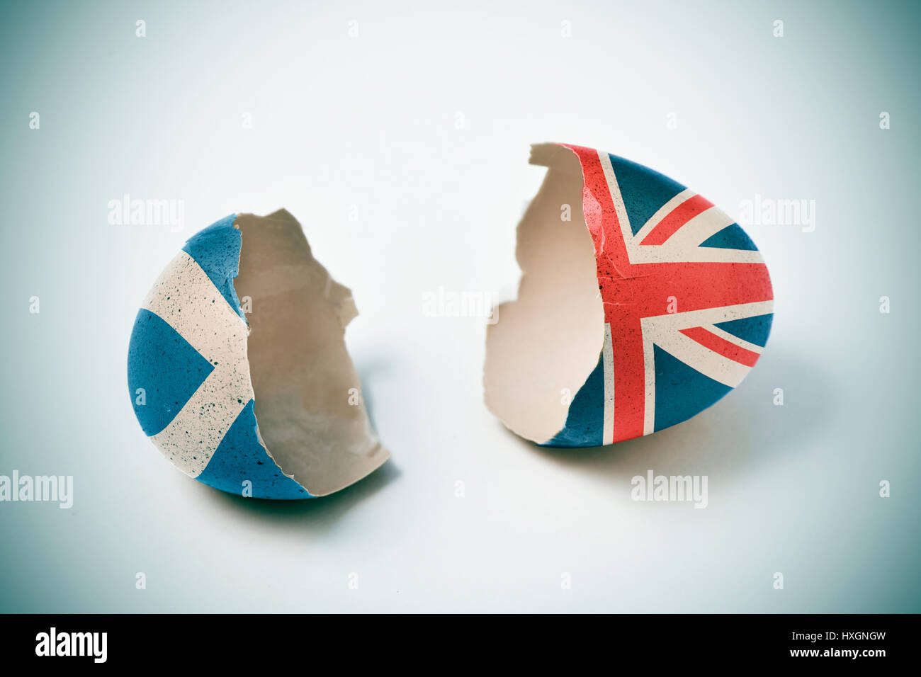 the two halves of a cracked eggshell, one patterned with the flag of Scotland and the other one patterned with the flag of United Kingdom Stock Photo