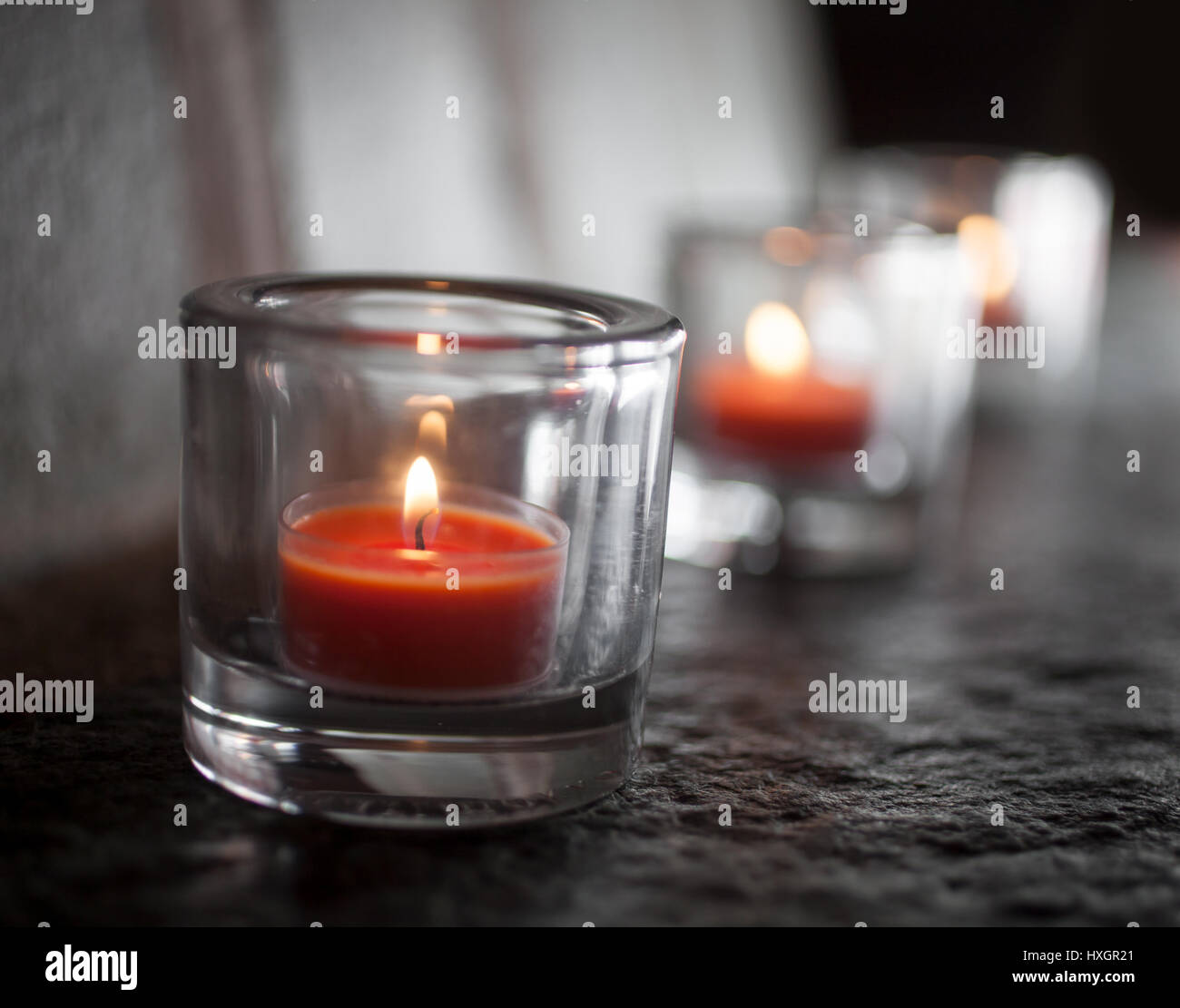 Three tealights burning and glowing in the dark Stock Photo